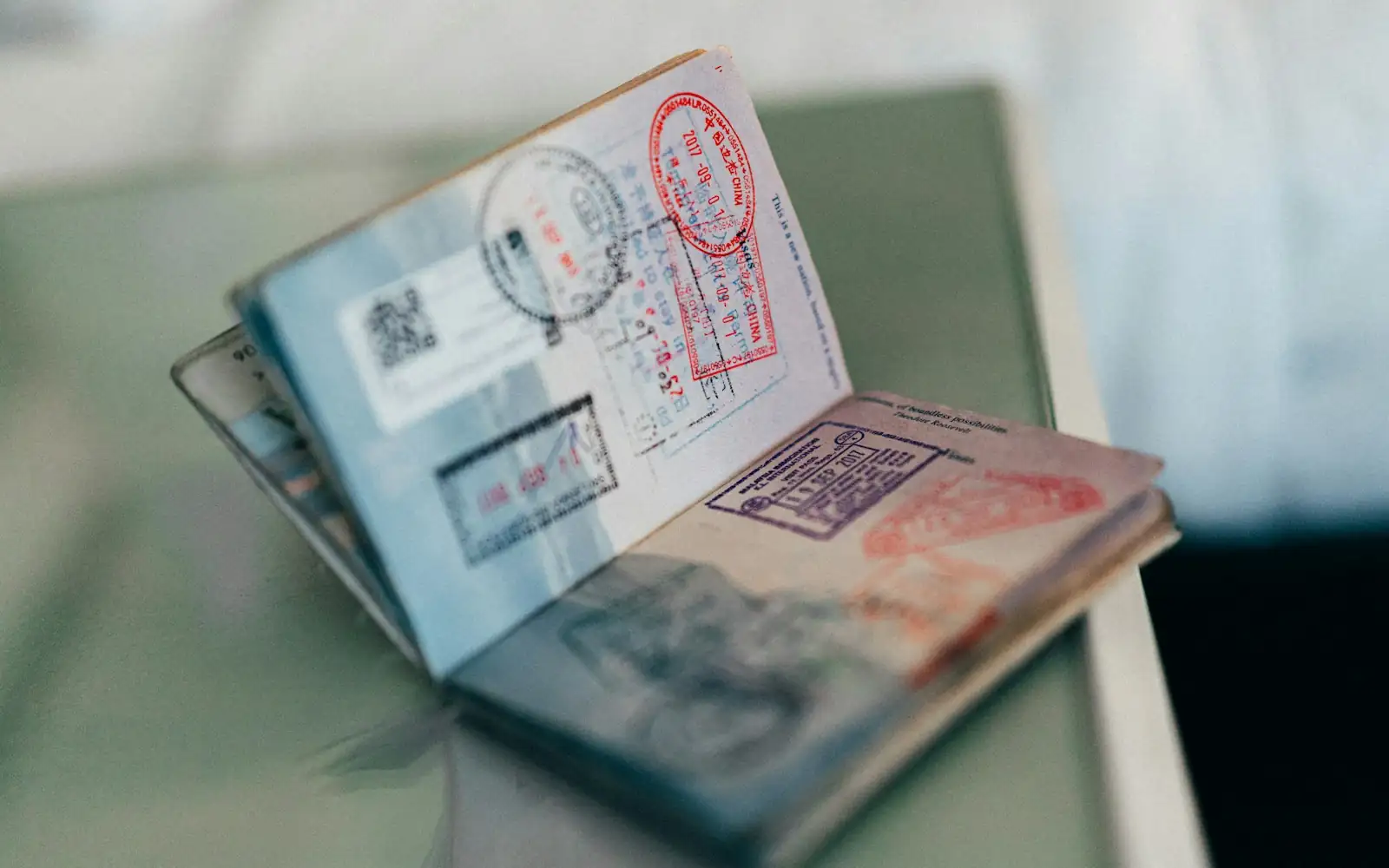 Open passport showing pages filled with colourful immigration entry and exit stamps
