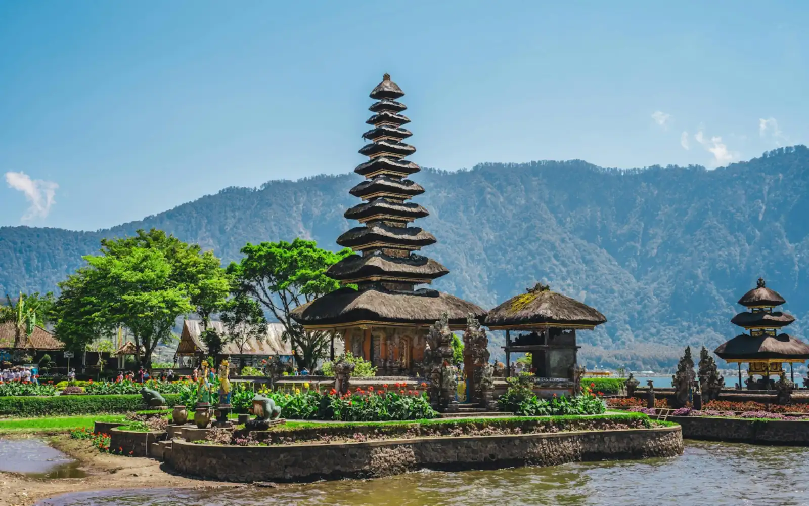 Multi-tiered meru shrine of Pura Ulun Danu Beratan on the lake shore with forested hills behind