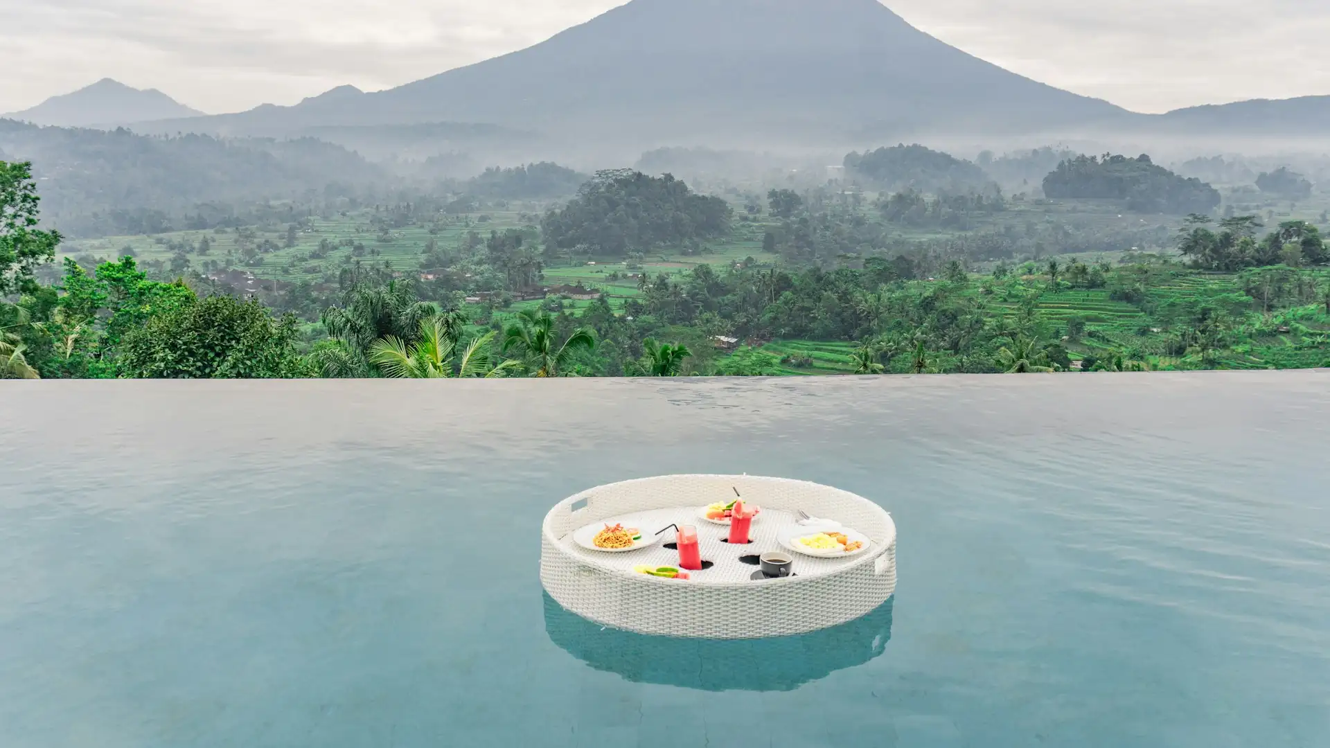 Floating breakfast tray in an infinity pool overlooking rice fields and Mount Agung in east Bali
